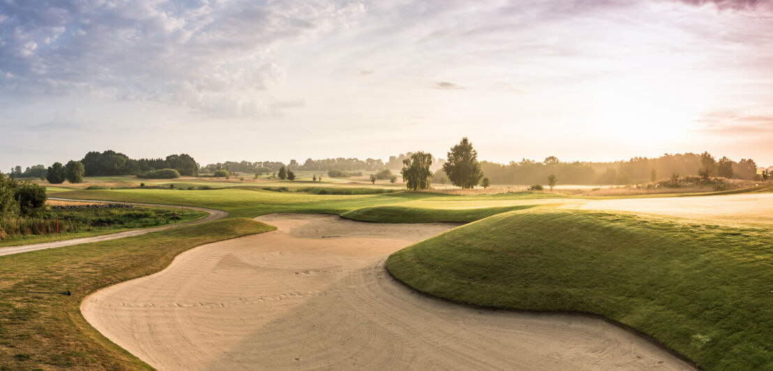 Blick auf eine Golfbahn vom Sand aus