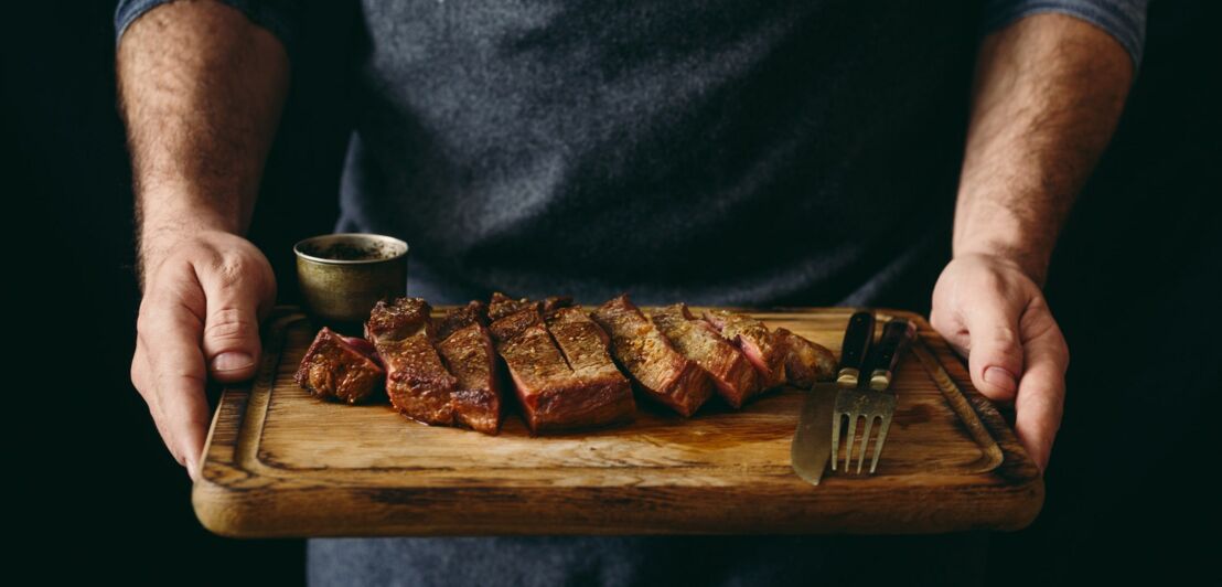 Saftig gegrilltes Rindersteak auf einem Holzbrett mit Gewürzen