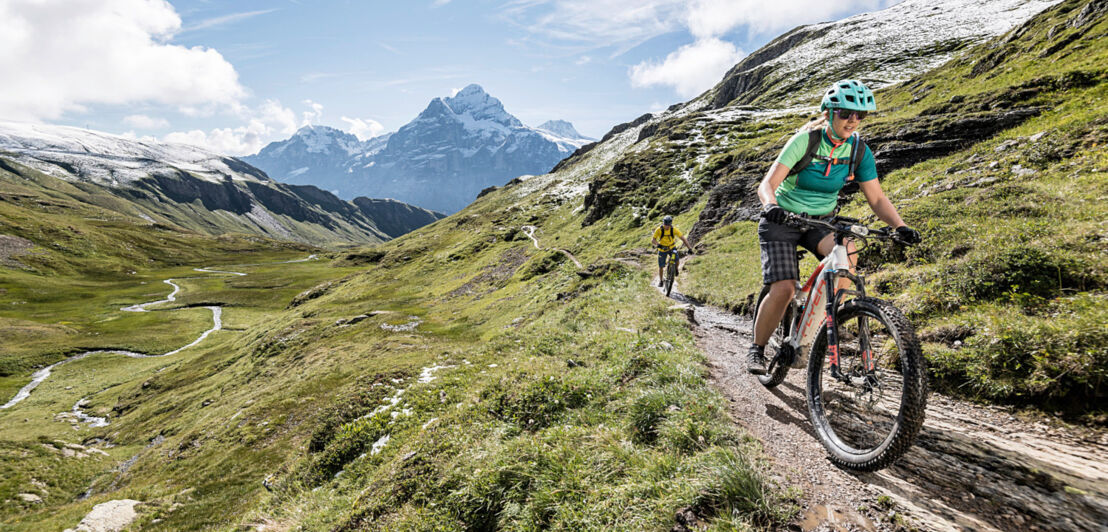 Eine Frau fährt auf einem Mountainbike einen Bergweg entlang