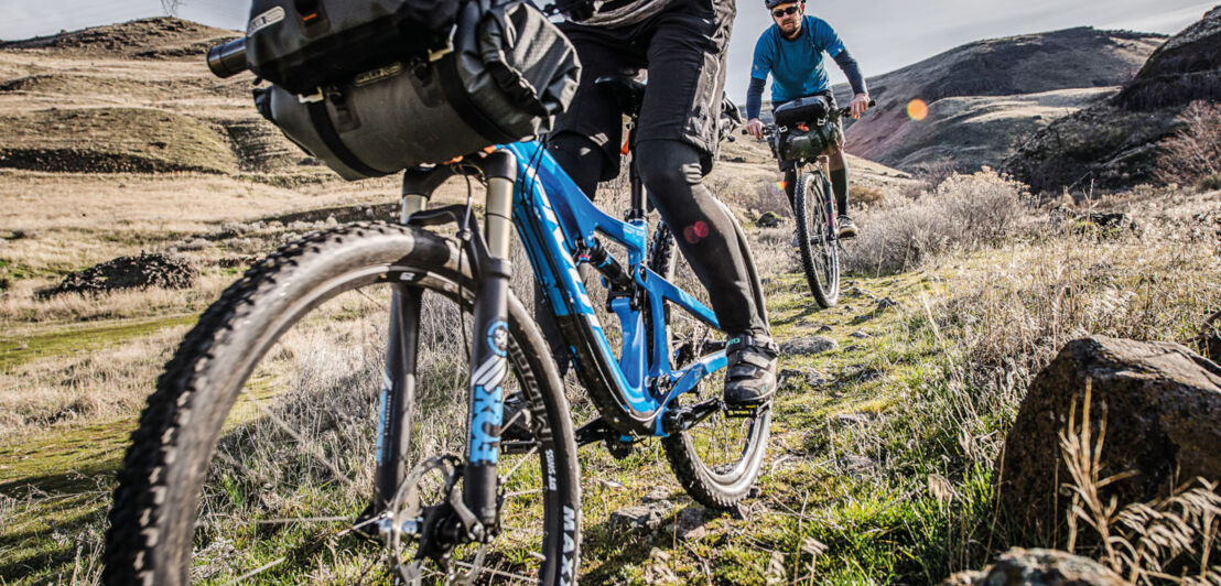 Zwei E-Mountainbikes hintereinander fahrend in einer kargen Berglandschaft