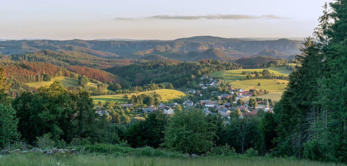 Blick auf einen idyllisch in bewaldeten Hügeln gelegenen Ort