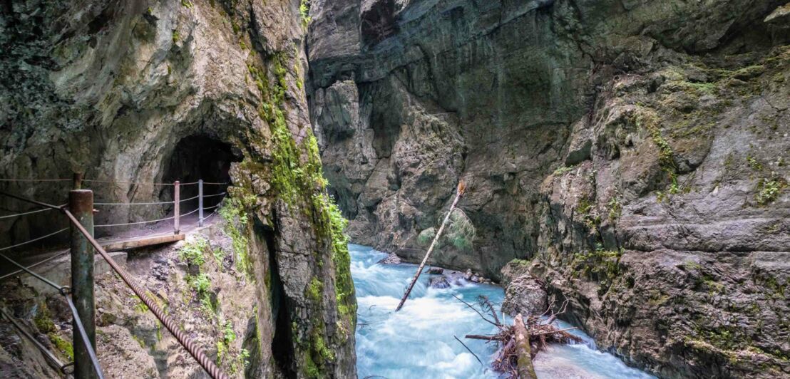 Ein Wanderweg führt über einen Steg und durch einen Tunnel durch die Partnachklamm