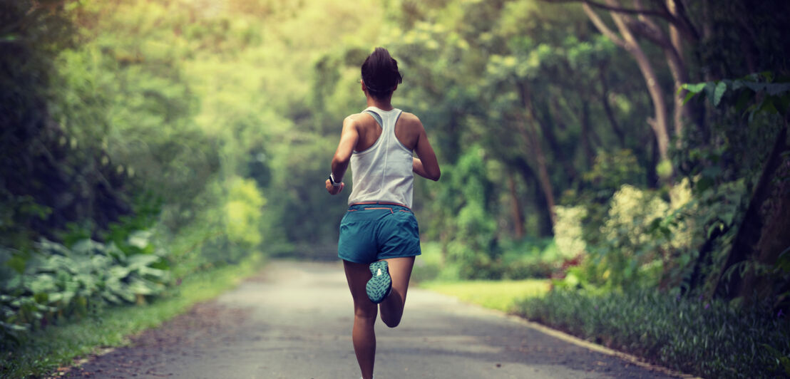 Eine Frau mit Smartwatch joggt eine Straße entlang