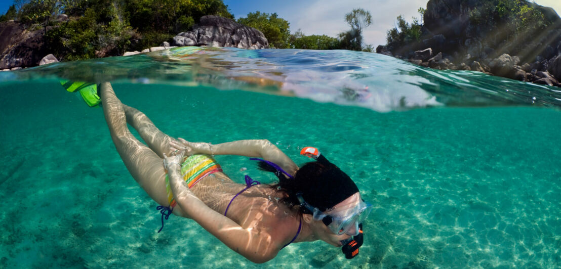 Frau schnorchelt vor einer tropischen Insel