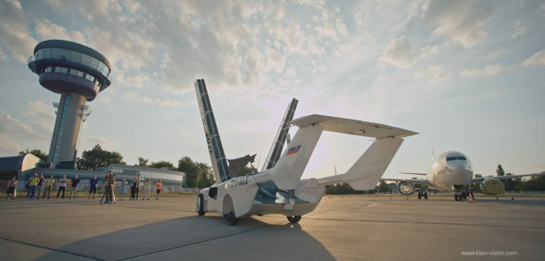 Ein AirCar mit hochgeklappten Flügeln steht auf einer Landebahn