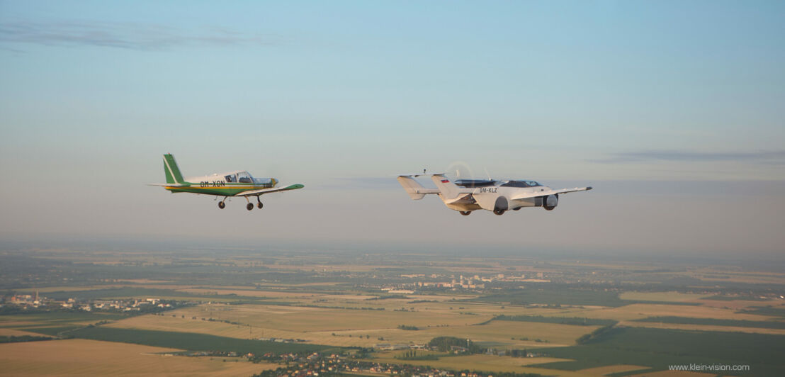 Ein AirCar Flugauto neben einem Sportflugzeug in der Luft