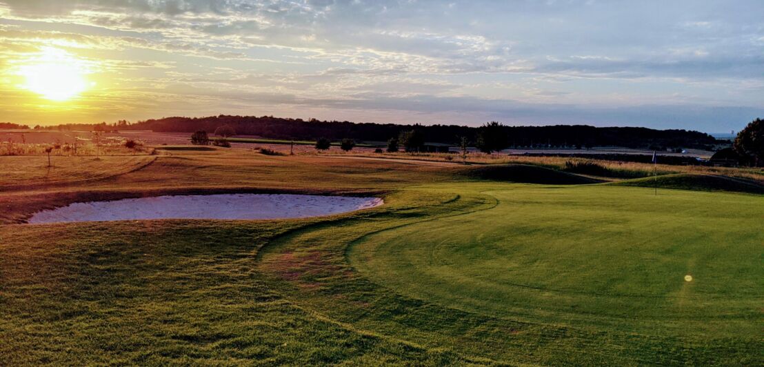 Ein Golfplatz mit Bunker bei Sonnenuntergang