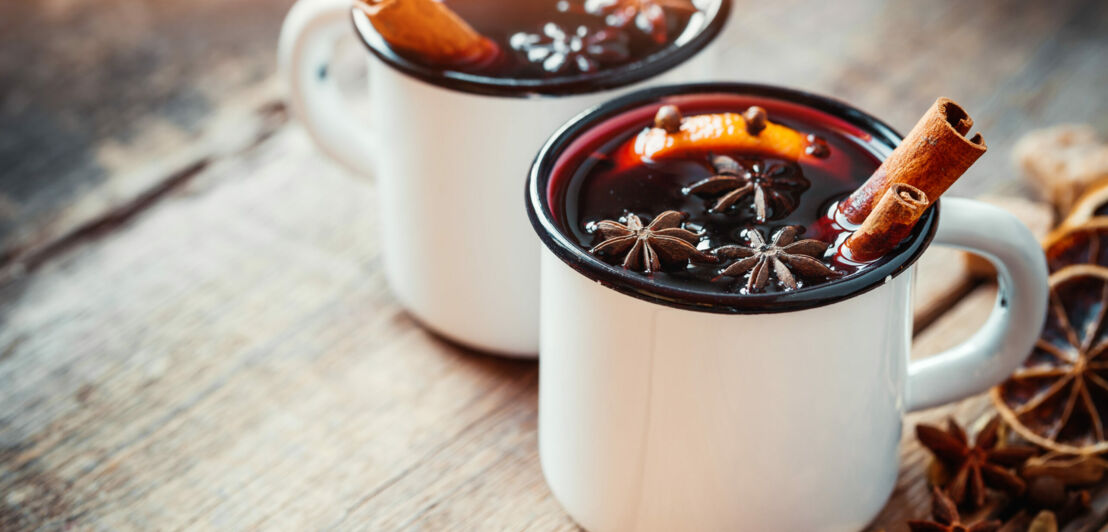 Zwei Tassen Punsch mit Orangenscheiben und Gewürzen