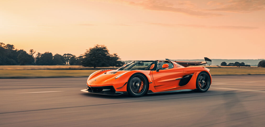 Ein Koenigsegg Jesko in Orange fährt auf einem Flugfeld