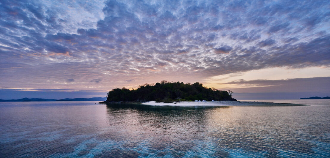 Eine tropische Insel mit Bäumen und Sandstrand in der Abenddämmerung