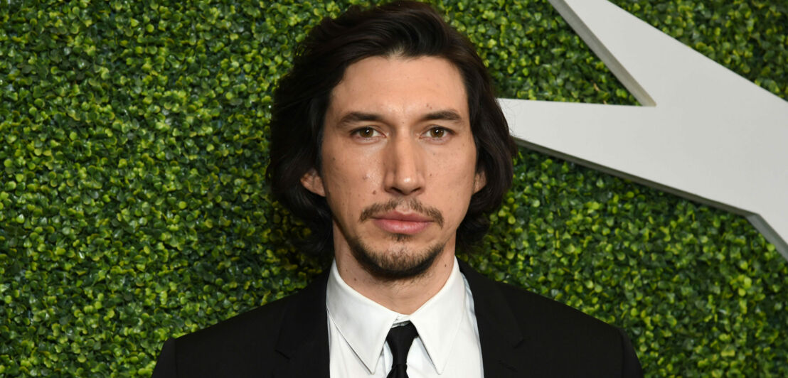 Porträt von Adam Driver mit Bart und Anzug vor grünem Hintergrund.