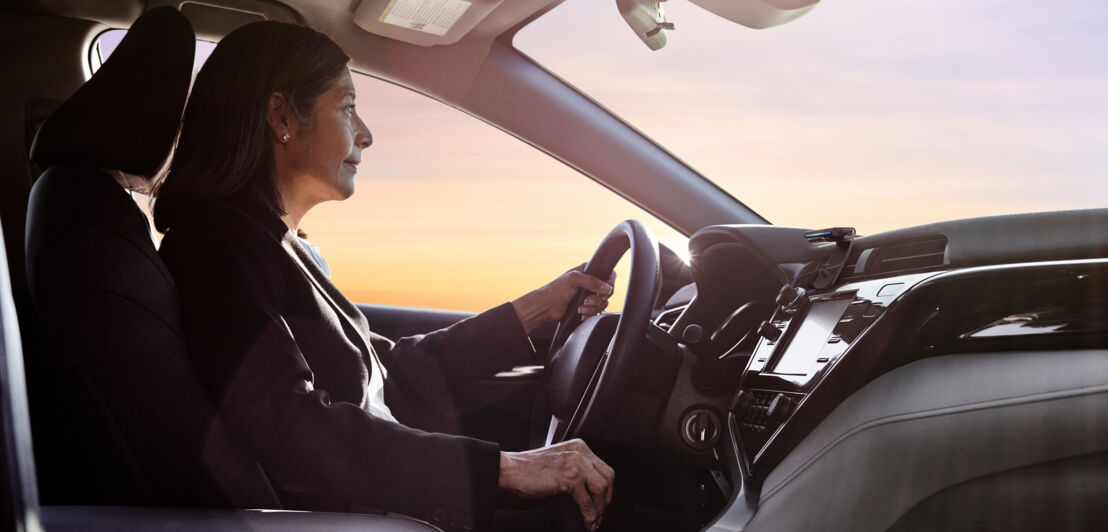 Eine Frau steuert einen PKW, in dem Echo Auto montiert ist.