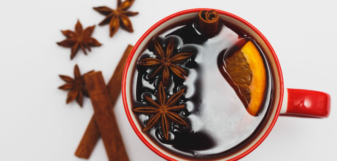 Glühbier mit Saft, Orange, Zitrone, Zimt und Sternanis in einer roten Tasse