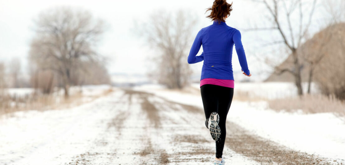 Joggerin von hinten auf einem verschneiten Weg