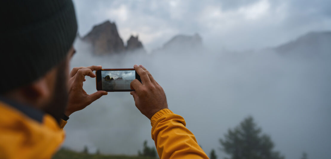 Ein Mann fotografiert mit seinem Smartphone.