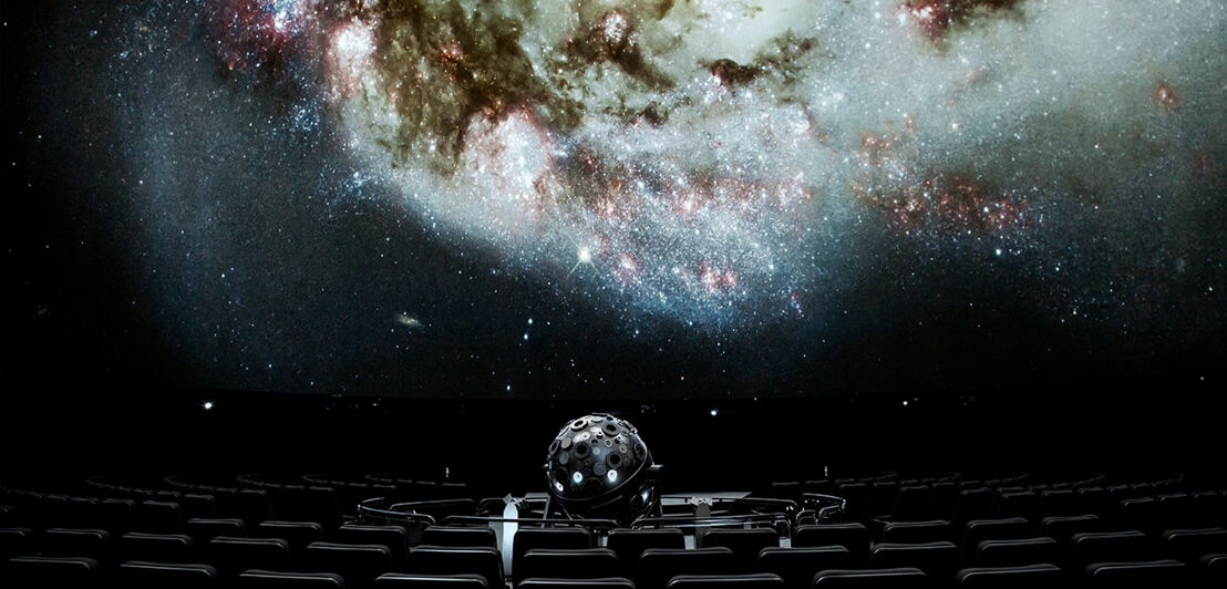 Planetariumssaal mit Sitzen, Projektor und Sternenhimmel