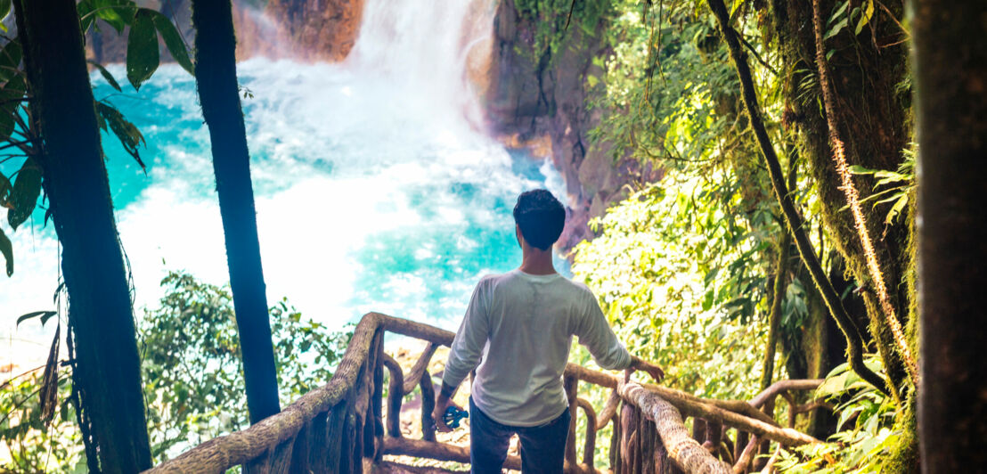 Ein Mann auf einer Holztreppe. Unten ist ein Wasserfall