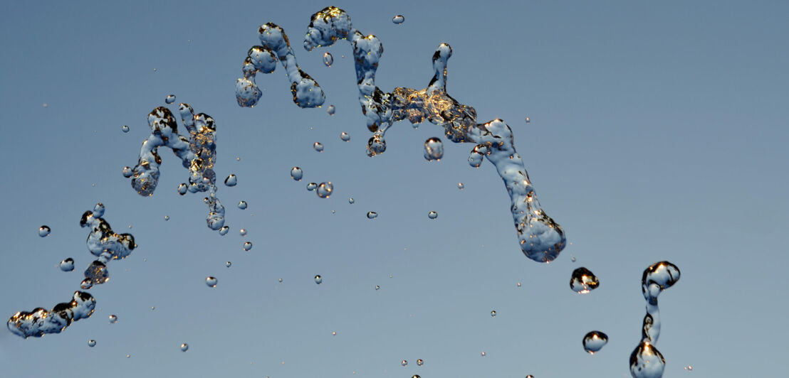 In der Luft hängende Wassertropfen vor blauem Hintergrund.