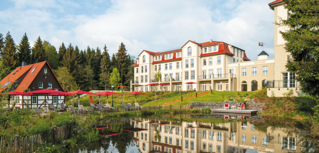 Luxuriöse Hotelanlage mit Badeteich, umgeben von Wald