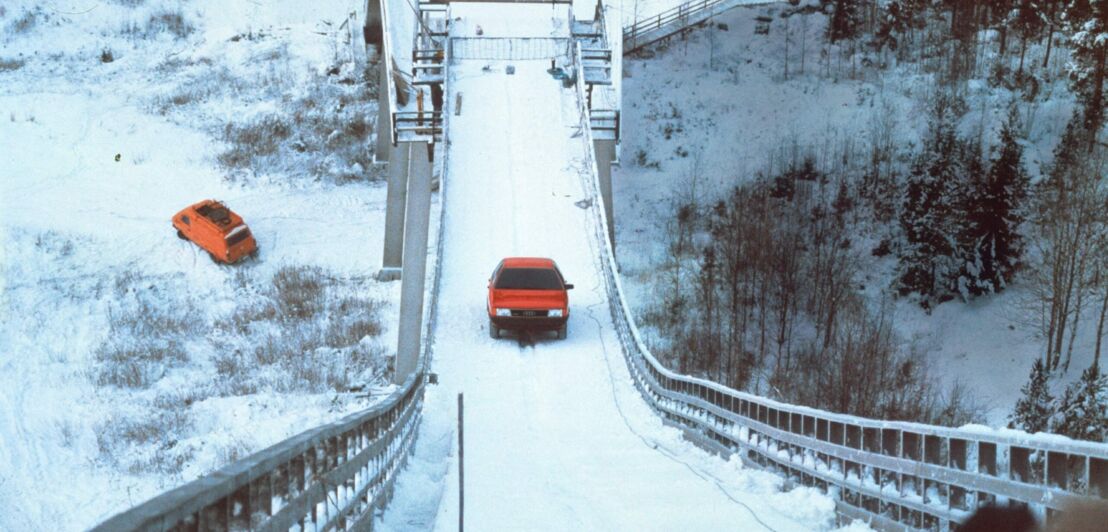 Ein Audi 100 Quattro fährt eine Sprungschanze hinauf.