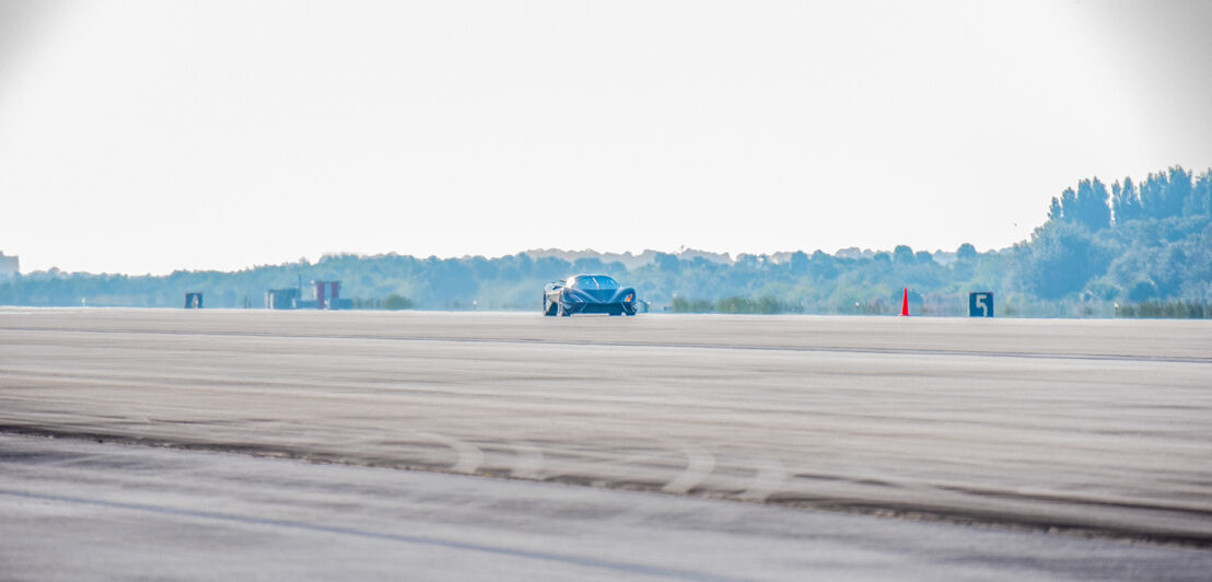 Der SSC Tuatara auf einer Rennstrecke, im Hintergrund eine Waldlandschaft.