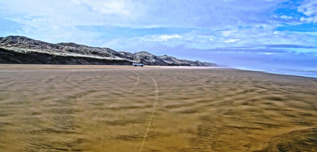 Ein Auto fährt auf dem Ninety Mile Beach.