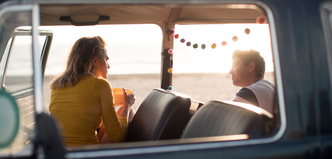 Ein Paar in einem Camper am Strand