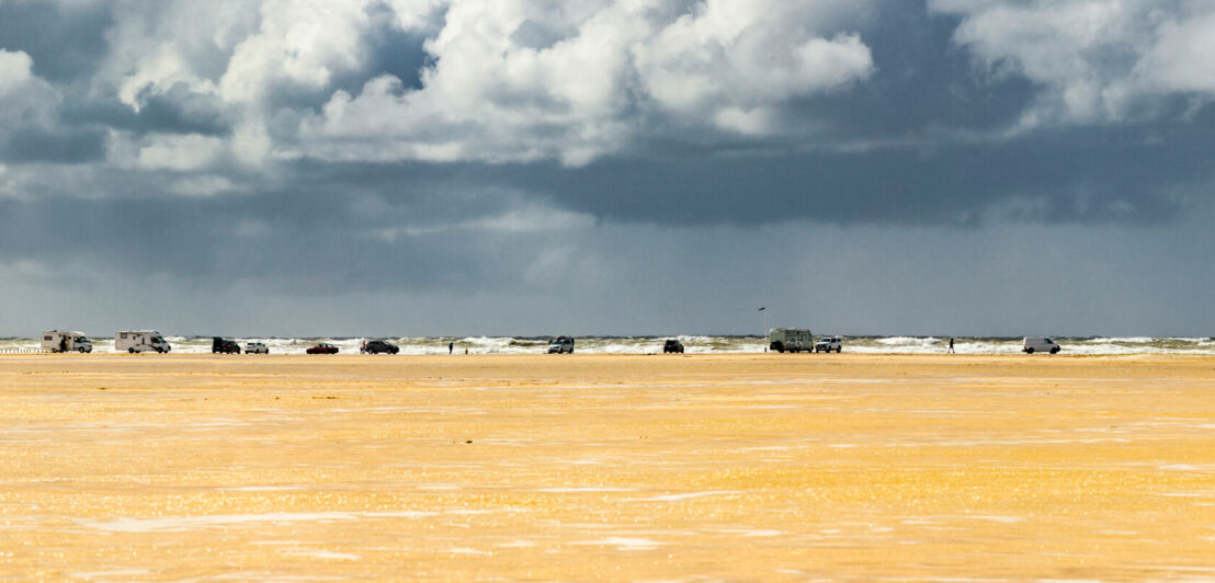 Der Strand von Rømø mit mehreren Fahrzeugen.