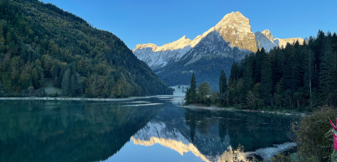 Ein See in bewaldeter Berglandschaft bei Dämmerung