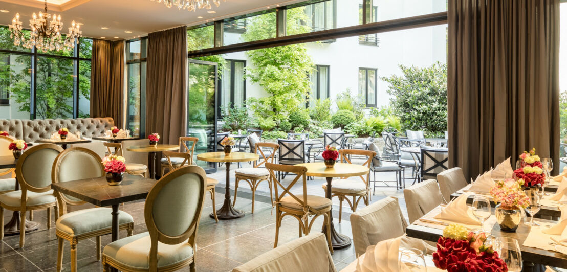 Blick durch den halboffenen Wintergarten mit stilvollem Interieur auf die Terrasse und den begrünten Innenhof