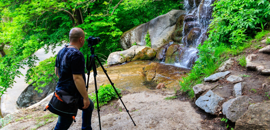 Ein Fotograf an einem Wasserfall.