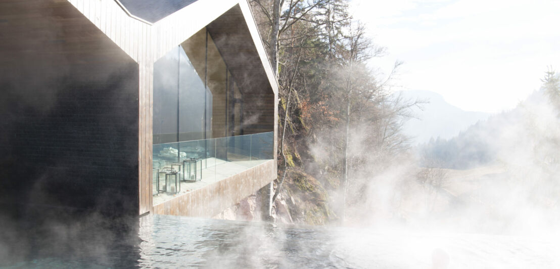 In einem Pool ohne Geländer mit Blick über die Berge schwimmt ein Mensch