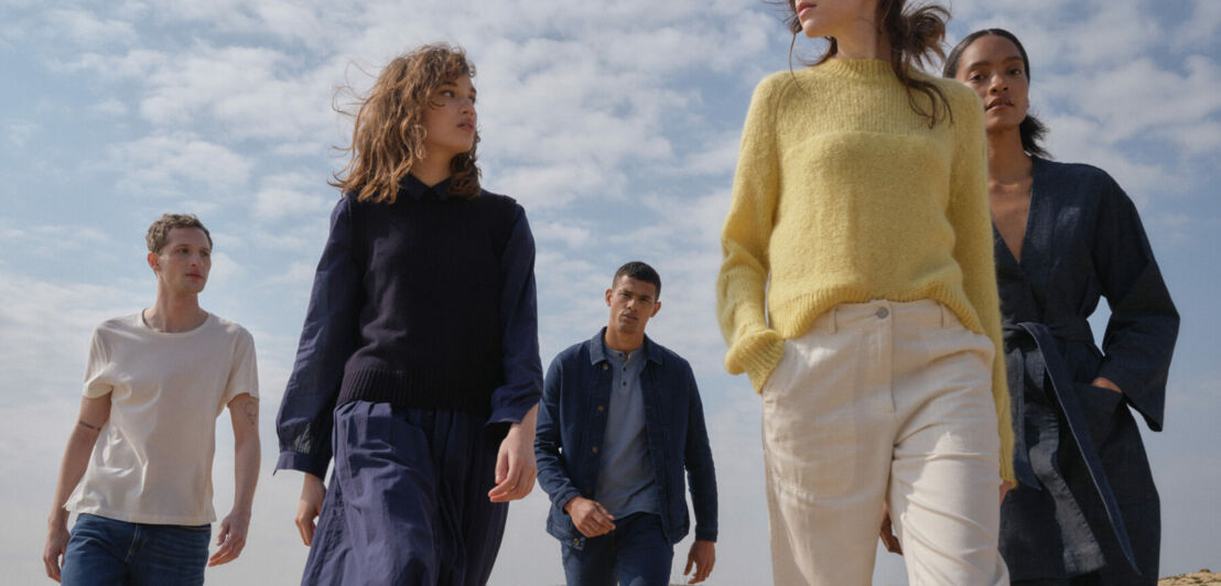 Mehrere Models am Strand, die alle unterschiedliche Outfits von Hessnatur tragen