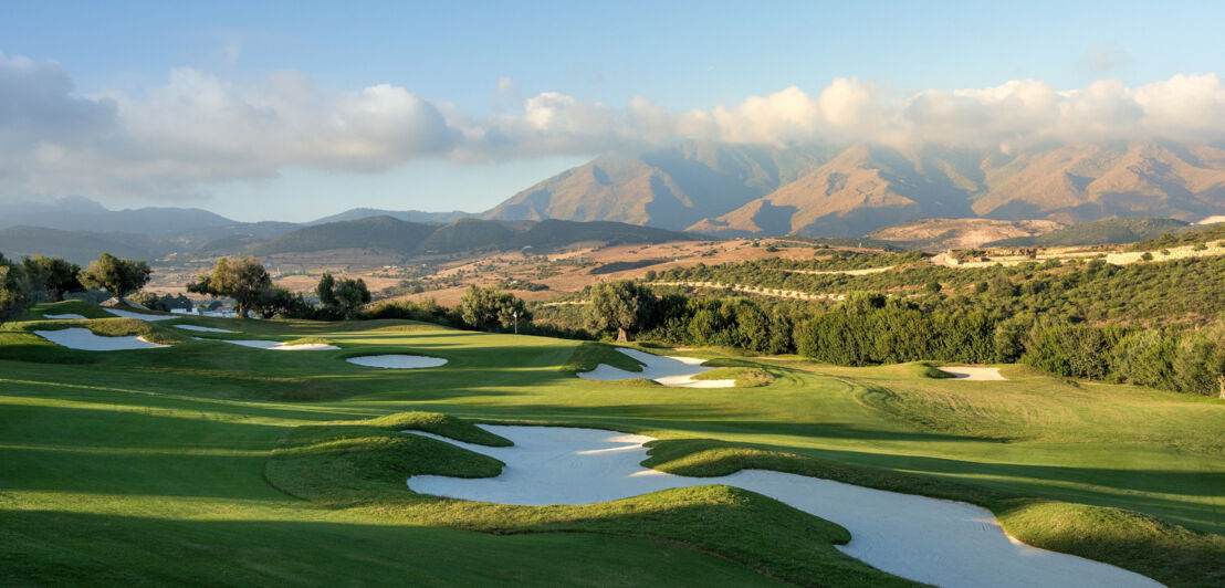 Ein Golfplatz vor einer Bergkulisse