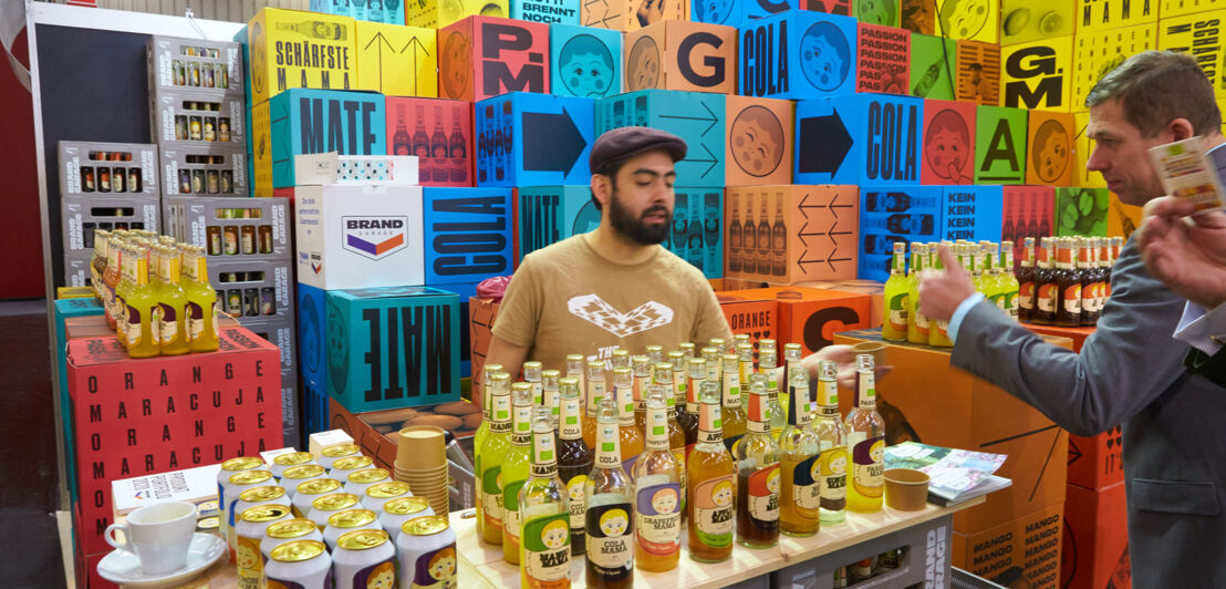 Messestand mit diversen Getränken und bunter Deko im Hintergrund