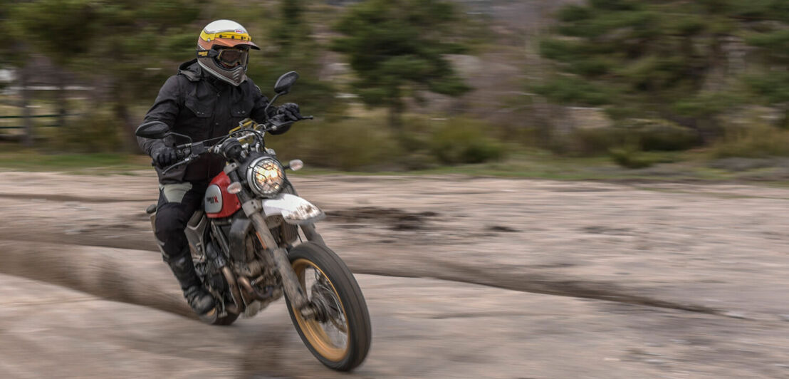 Ein Motorradfahrer driftet auf einer roten Ducati über eine Sandpiste.