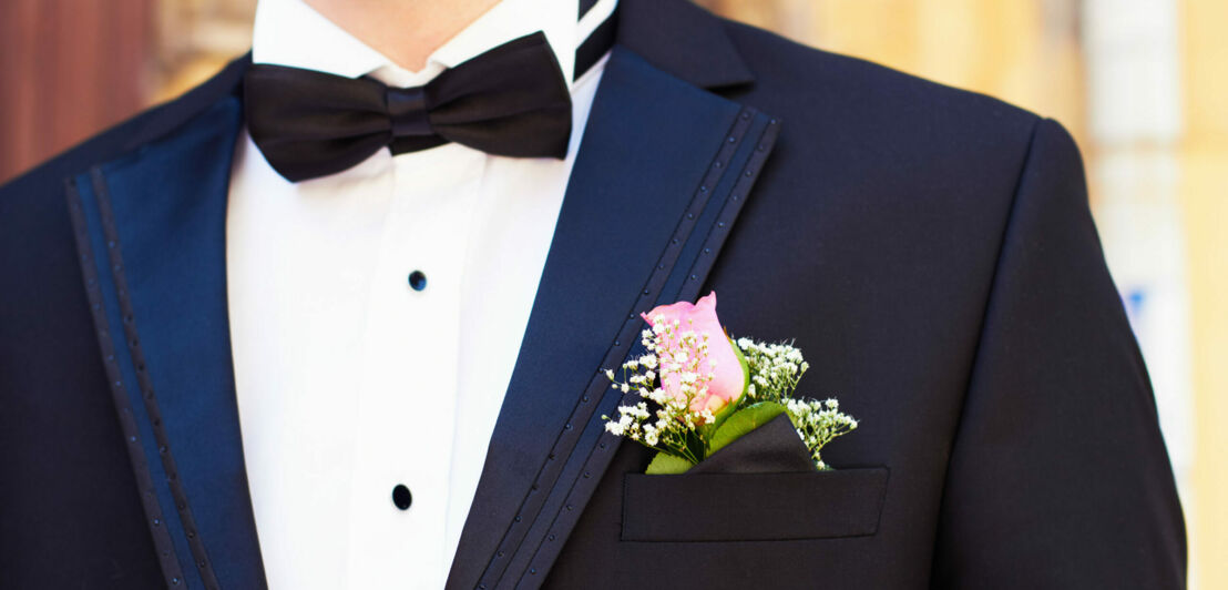 Brustporträt eines Mannes im blauen Smoking mit schwarzer Fliege, Einstecktuch und Blumenbouquet