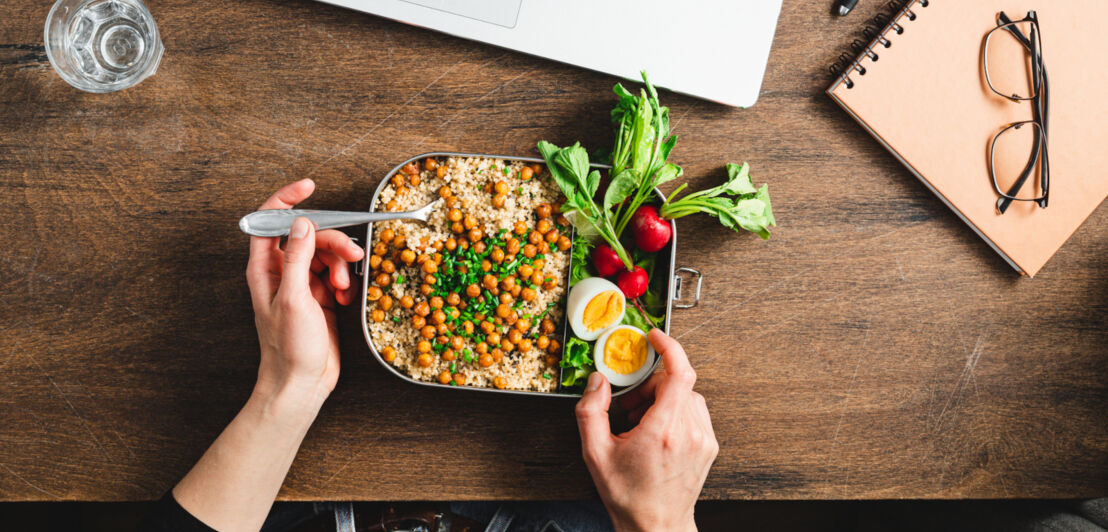 Aufsicht einer Person beim Essen einer gesunden Mahlzeit am Schreibtisch