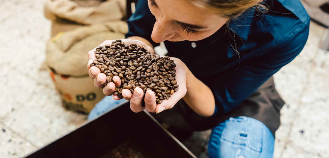 Eine Frau riecht an gerösteten Kaffeebohnen in ihrer Hand