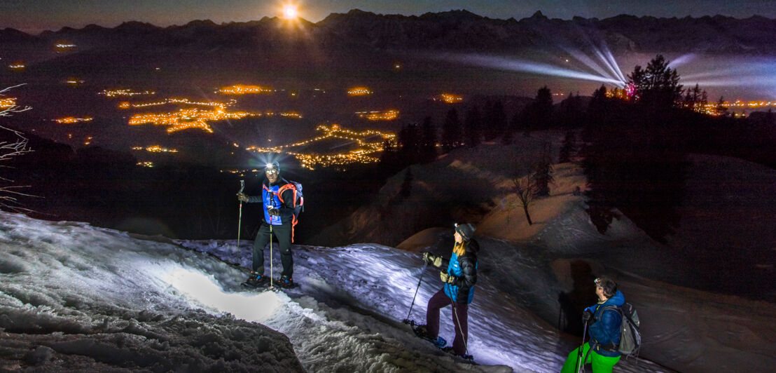 Drei Personen bei einer Schneeschuhwanderung bei Nacht