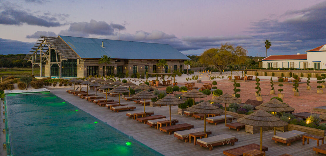 Eine Hotelanlage auf dem Land mit Pool, Sonnenliegen und Sonnenschirmen