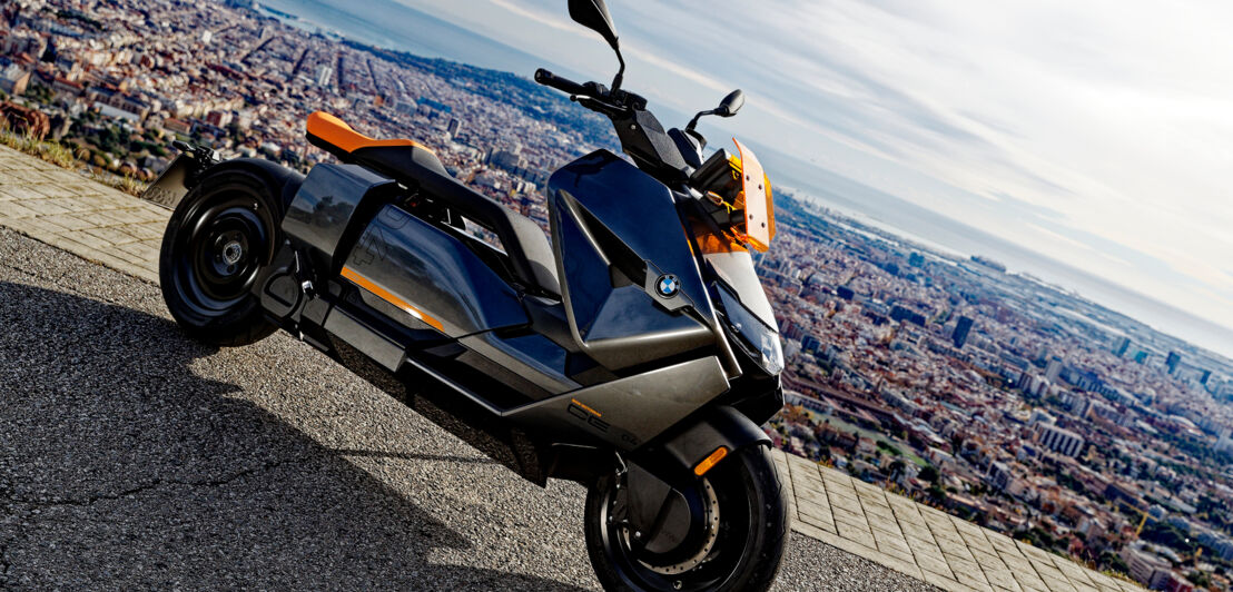 Der Elektro-Großroller BMW CE 04 parkt auf einem Plateau mit Blick auf Barcelona.