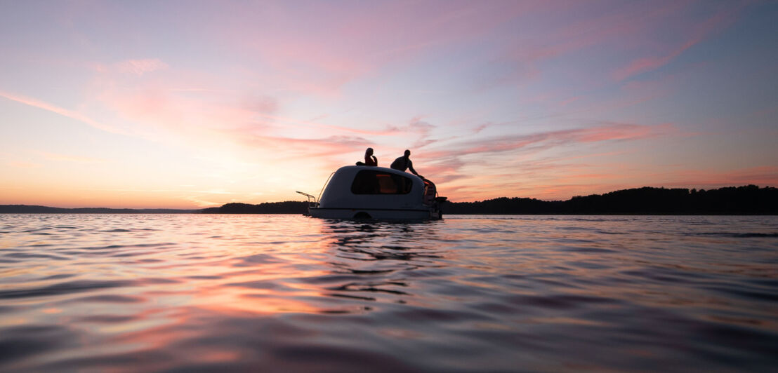 Ein Paar bei Sonnenuntergang auf dem Dach eines Schwimmwohnwagens