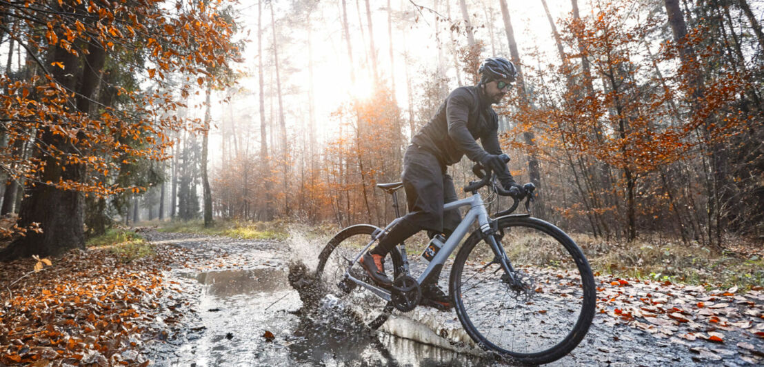 Ein Radfahrer fährt durch eine Pfütze.