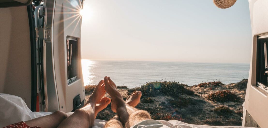 Ein Paar liegt in einem Camper am Meer