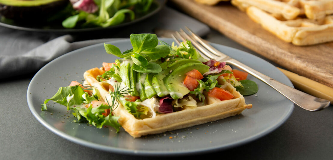 Eine mit Avocado und Salat belegte belgische Waffel.