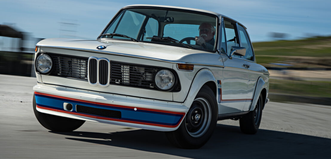 Ein weißer BMW 2002 auf einer Rennstrecke