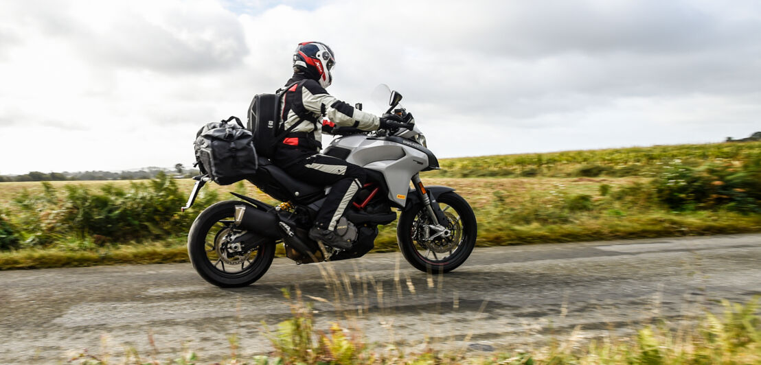 Ein Motorradfahrer fährt von links nach rechts auf einer Ducati Multistrada 950 (V2) durchs Bild.