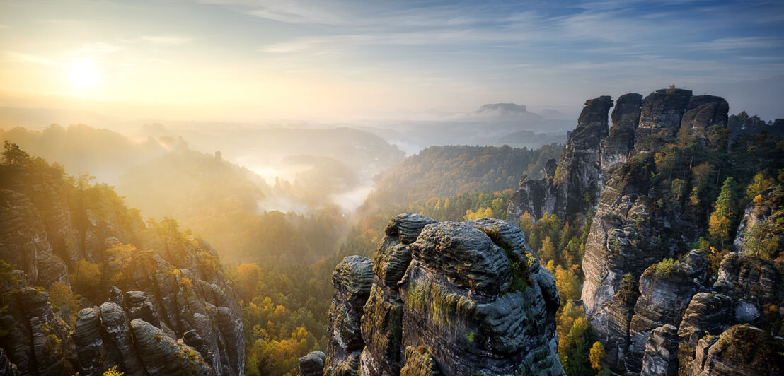 Blick auf das Elbsandsteingebirge mit Nebelschwaden bei Sonnenuntergang.