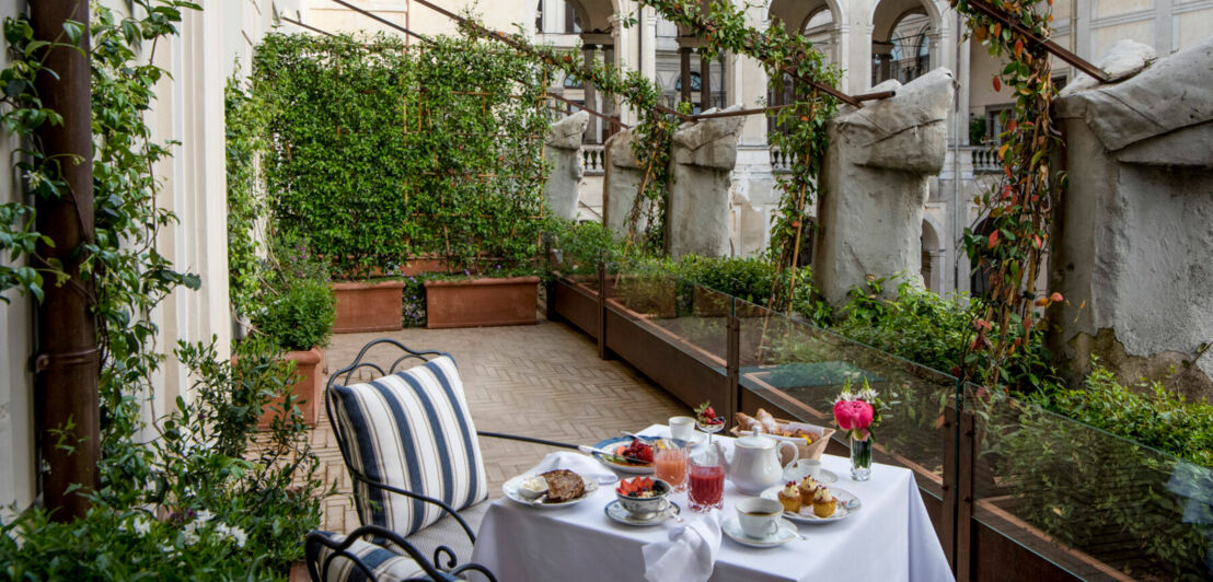 Ein gedeckter Frühstückstisch auf einer zum Innenhof ausgerichteten privaten Terrasse